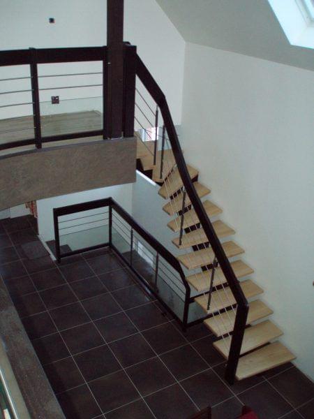 Escalier bois à limon central. Limon et rampe en teinté noir. Remplissage en balustres bois et lisses inox. Marches en frêne massif.