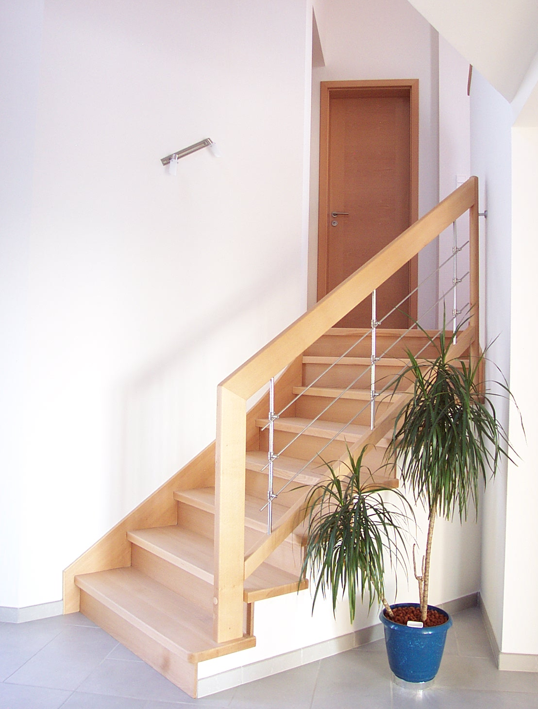 Habillage de marches et contremarches en hêtre massif sur escalier béton. Rampe en bois avec remplissage avec balustres et lisses inox sur liens.