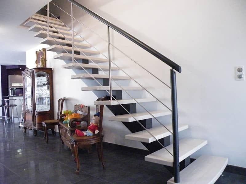 Escalier bois à limon central. Limon et rampe en bois laqué anthracite. Main-courante ronde et remplissage en lisses inox. Marches en bois teintés blanches.